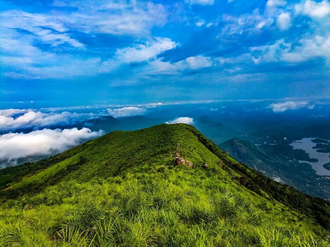 Ilaveezhapoonchira misty landscape at sunrise with rolling green hills and panoramic valley view in Kottayam, Kerala.
